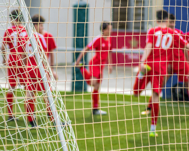 football players stretching shown through football goal netting